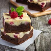 raspberry cheesecake brownies in a stack over a parchment paper