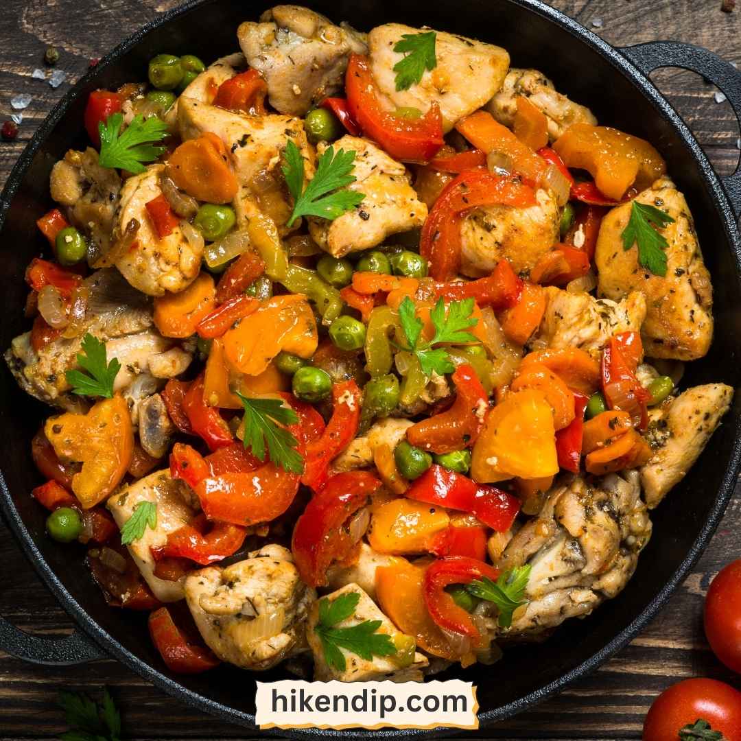 chicken and vegetable stir fry in a skillet with herbs as garnish