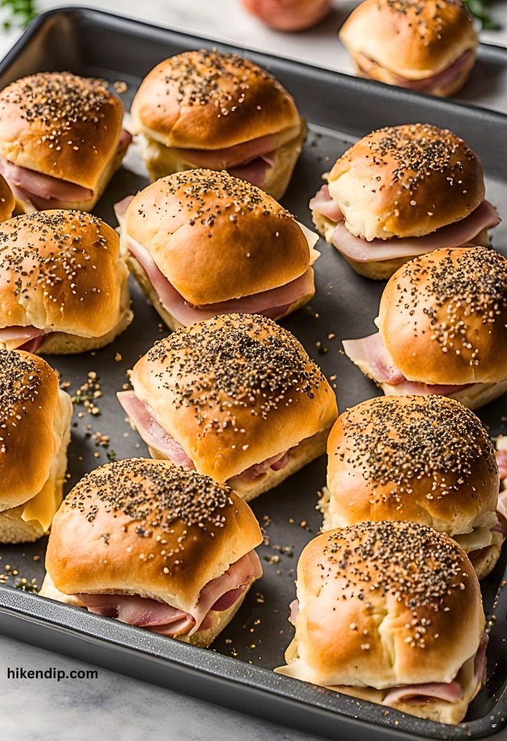 ham and cheese sliders with poppy seeds on a baking tray